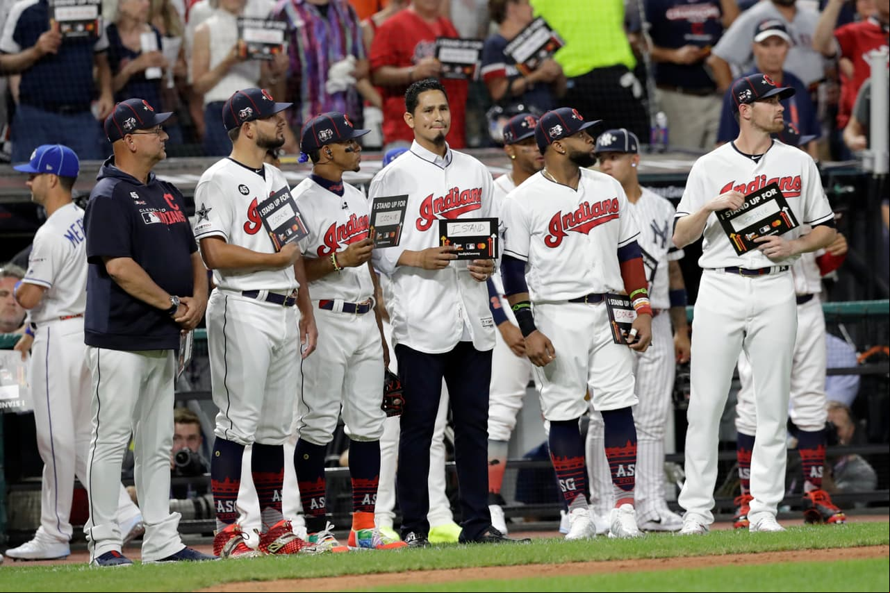 Carlos Carrasco, al centro sin gorra, de los Cleveland Indians, está parado junto a sus compañeros en el quinto inning del MLB All-Star Game, en medio de la campaña "Stand Up to Cancer". Hace días le diagnosticaron leucemia.