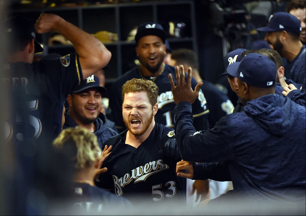 El pitcher ganador y el jugador clave del partido, el relevista Brandon Woodruff (centro) celebra su cuadrangular en la victoria de los Milwaukee Brewers.