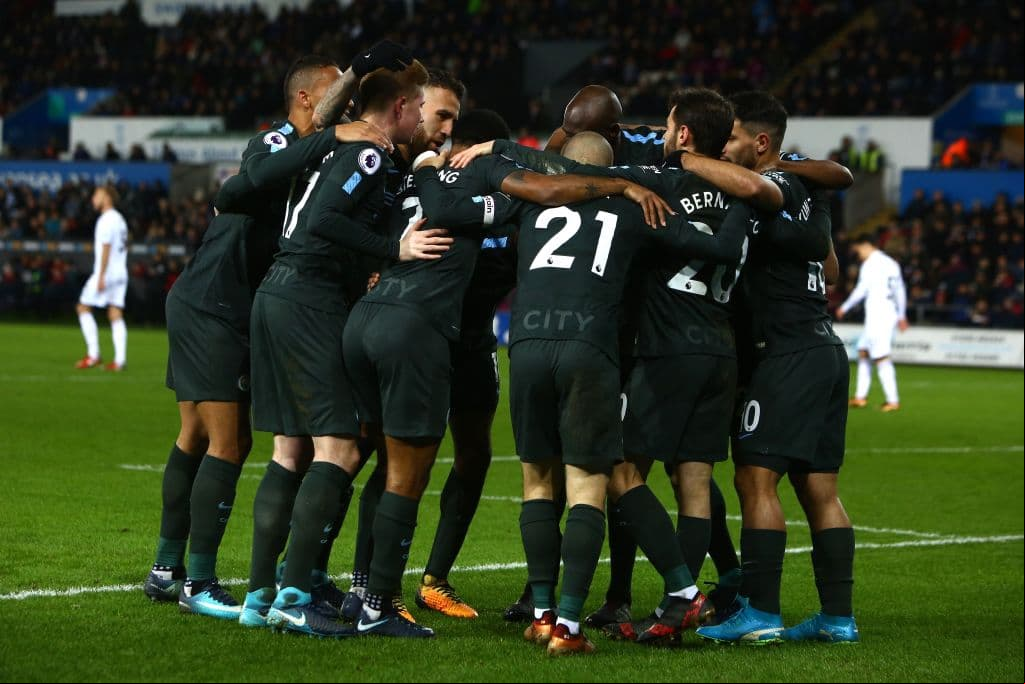 Manchester City's Spanish midfielder David Silva (C) celebrates after scoring their third goal with teammates during the English Premier League football match between Swansea City and Manchester City at The Liberty Stadium in Swansea, south Wales on December 13, 2017. / AFP PHOTO / Geoff CADDICK / RESTRICTED TO EDITORIAL USE. No use with unauthorized audio, video, data, fixture lists, club/league logos or 'live' services. Online in-match use limited to 75 images, no video emulation. No use in betting, games or single club/league/player publications. / (Photo credit should read GEOFF CADDICK/AFP/Getty Images)