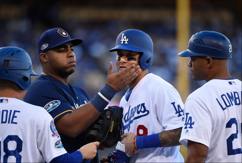 LOS ANGELES, CA - OCTOBER 15: Jesus Aguilar #24 of the Milwaukee Brewers pats the face of Manny Machado #8 of the Los Angeles Dodgers at first base during the second inning of Game Three of the National League Championship Series at Dodger Stadium on October 15, 2018 in Los Angeles, California. (Photo by Kevork Djansezian/Getty Images)